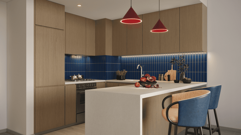 Une cuisine moderne avec des armoires en bois, un dosseret en carrelage bleu et un comptoir blanc. L'espace est mis en valeur par des suspensions rouges au-dessus d'un bar avec deux tabourets bleus, parfaits pour un investissement immobilier.