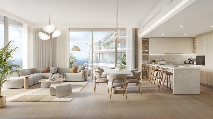 Salon et cuisine décloisonnés modernes avec lumière naturelle, dotés d'un mobilier élégant, d'un îlot de cuisine et de grandes fenêtres donnant sur un balcon avec des plantes. Une palette de couleurs neutres crée une atmosphère calme dans cette villa Dubaï
