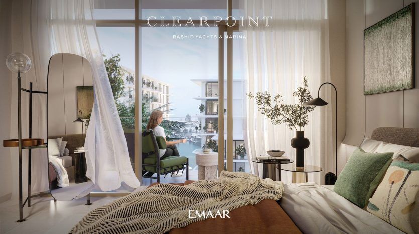 Luxurious bedroom interior with a modern design aesthetic in a Dubai apartment. A woman sits by the window, overlooking a marina. The room features elegant furnishings and decorative accents, creating a stylish and