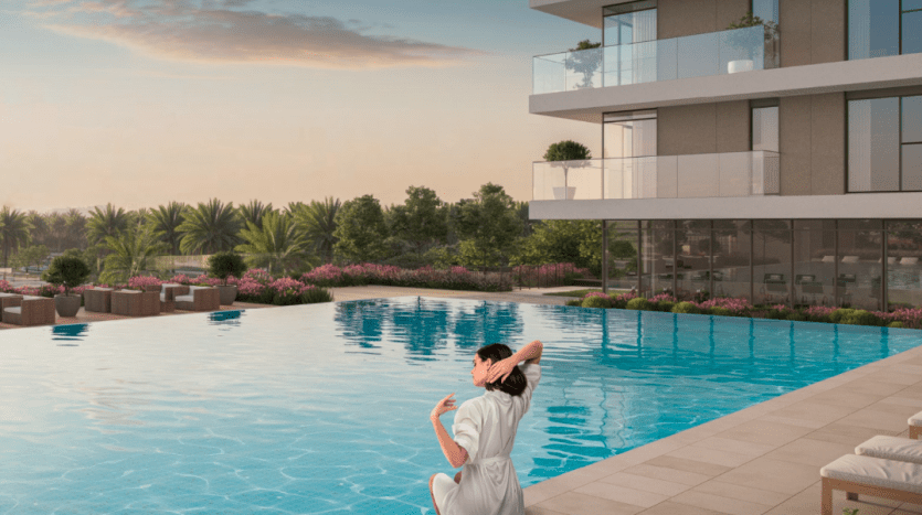 Une femme vêtue d'une robe blanche est assise au bord d'une piscine luxueuse au coucher du soleil, regardant un paysage serein avec une verdure luxuriante et des fleurs roses. Un bâtiment architectural moderne avec des balcons en arrière-plan, caractéristique
