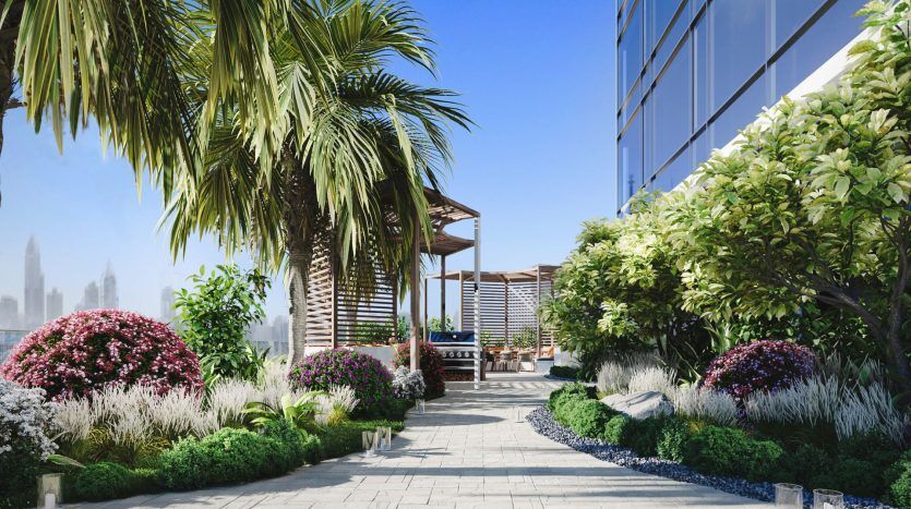 Un jardin luxuriant sur le toit avec un belvédère en bois, aménagé de fleurs et de verdure colorées, adjacent à un bâtiment moderne en verre à Dubaï, sous un ciel bleu clair.