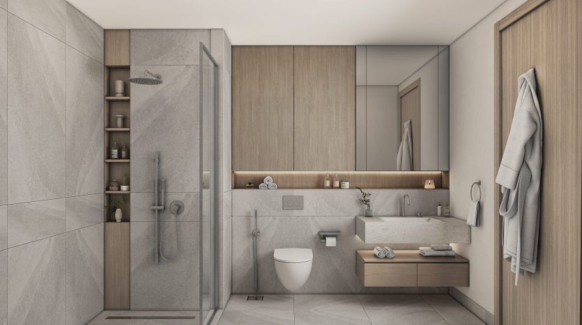 Intérieur de salle de bains moderne dans un appartement de Dubaï avec douche à l'italienne, armoires en bois, lavabo, grand miroir et toilettes blanches. Les tons neutres et les lignes épurées dominent l'espace.