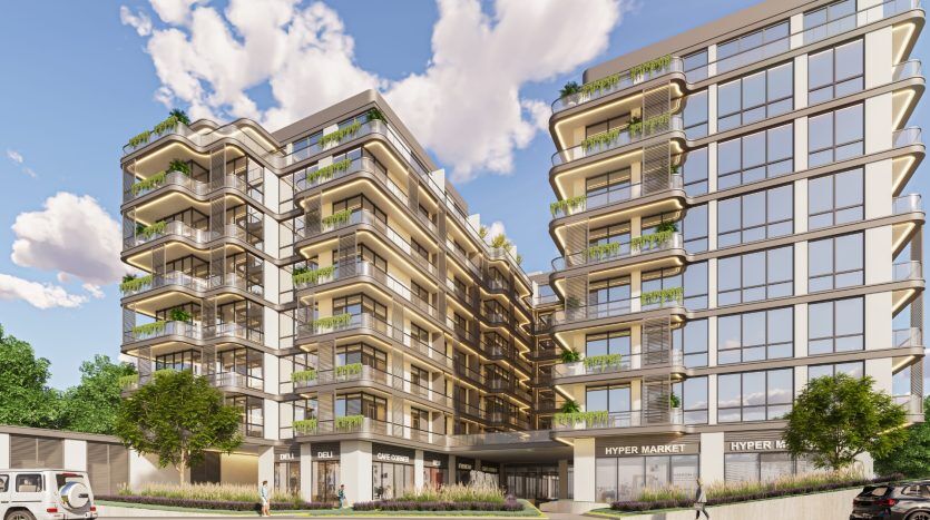 Un bâtiment moderne de plusieurs étages présentant un mélange de balcons avec des plantes et des façades en verre élégantes, situé au-dessus d'un hypermarché au rez-de-chaussée à Dubaï, sous un ciel bleu clair.