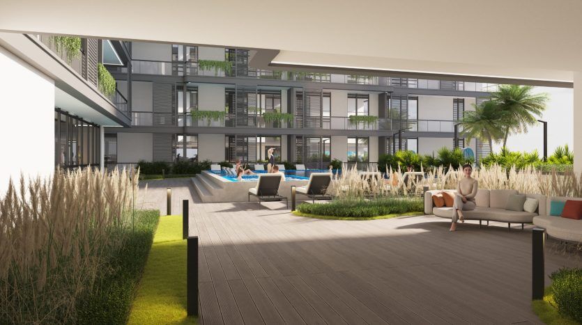 Un complexe d'appartements moderne à Dubaï comprenant des coins salons avec des canapés, des plantes vertes, des palmiers et des résidents qui se détendent. Le bâtiment comporte plusieurs étages avec balcons.