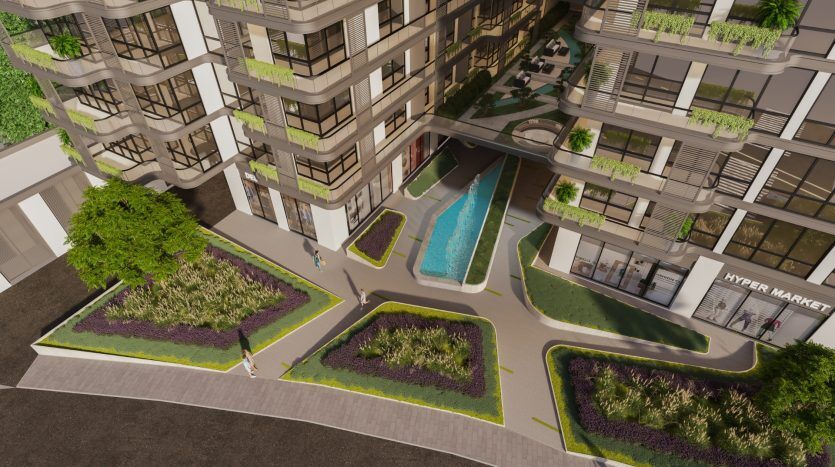Vue aérienne d'un complexe d'appartements moderne doté d'une piscine centrale, de jardins luxuriants et d'un hypermarché, entouré d'immeubles de plusieurs étages avec balcons à Dubaï.