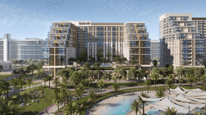 Vue aérienne d'un développement urbain moderne comprenant des immeubles de grande hauteur portant le logo « emaar », entourés d'une verdure luxuriante, de palmiers et de personnes profitant d'une journée ensoleillée avec une grande piscine
