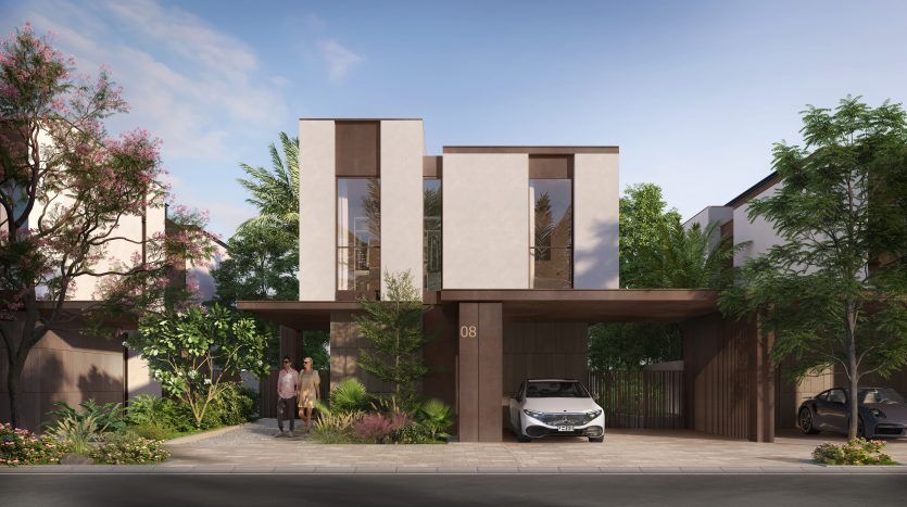 Villa moderne de deux étages à Dubaï avec un grand patio avant, présentant une conception architecturale épurée et géométrique, entourée d'un aménagement paysager luxuriant. Un couple se tient à l’entrée avec des voitures garées à proximité.