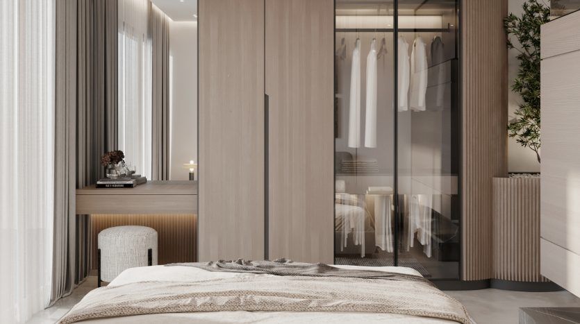 Chambre moderne comprenant un lit avec des draps beiges, une élégante table de nuit en bois et une armoire en verre révélant des vêtements soigneusement suspendus. Un éclairage naturel doux et un décor minimaliste créent une ambiance sereine, idéale pour l'investissement