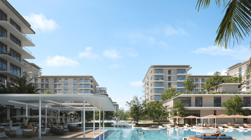 Un complexe luxueux composé de bâtiments modernes entourant une grande piscine avec des chaises longues et un espace ombragé, sur fond de ciel bleu clair et de verdure luxuriante, parfait pour ceux qui s'intéressent à l'immobilier Dubaï.
