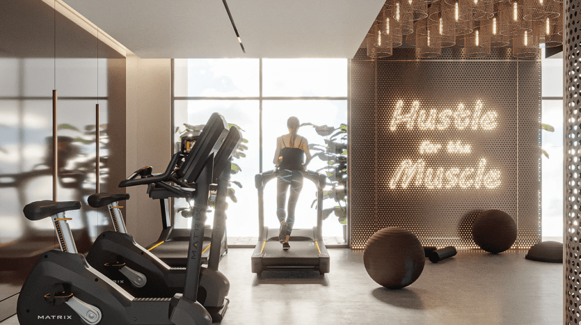 Une personne fait du jogging sur un tapis roulant dans une salle de sport moderne et bien équipée avec lumière naturelle dans un appartement haut de gamme à Dubaï. La salle de sport dispose d'autres équipements d'exercice et d'une enseigne au néon de motivation indiquant « hust
