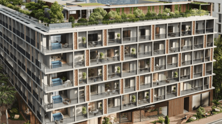Vue aérienne d'un immeuble d'appartements moderne de plusieurs étages à Dubaï, doté de balcons ornés de plantes, de balustrades en verre et de touches de briques distinctes.