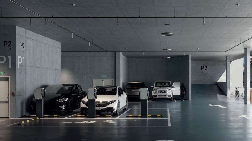 Spacieux parking souterrain dans une villa de Dubaï comprenant une gamme de voitures garées, notamment des modèles électriques et de luxe, avec des murs en béton et des sols clairement marqués.