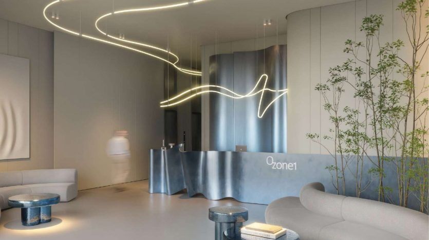 Espace de réception moderne dans une villa de Dubaï avec des luminaires courbes, un élégant bureau métallique marqué « Zone1 », des sièges gris doux et des plantes vertes, créant une ambiance sereine et aux tons frais.