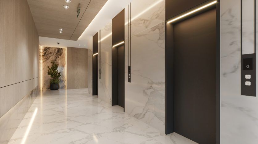 Hall d'entrée d'un bâtiment moderne avec sols en marbre poli, deux ascenseurs avec panneaux lumineux et une série de portes sur la droite. Une plante en pot ajoute une touche de verdure, idéale pour investir Dubaï