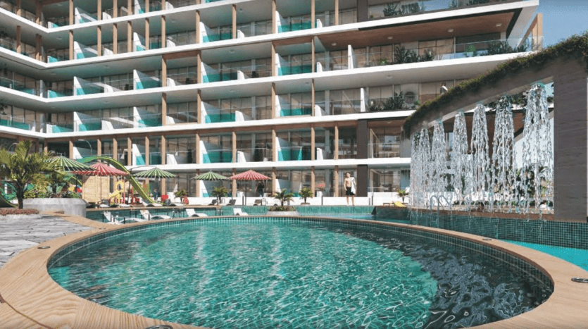 Un espace piscine d'hôtel luxueux avec une grande piscine au premier plan, entourée de parasols et de chaises longues, flanquée d'un bâtiment à plusieurs étages avec des balcons donnant sur la scène, évoquant le style d'un appartement haut de gamme de Dubaï.