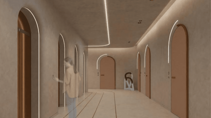 Un couloir moderne dans une villa à Dubaï, éclairé par des bandes LED continues au plafond, avec des portes cintrées et deux personnes floues en mouvement. Les murs ont un ton doux et terreux et le sol est de couleur claire.