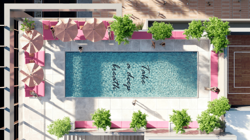 Vue aérienne d'une piscine entourée de chaises longues et de parasols roses, avec des gens nageant et se relaxant dans une luxueuse villa à Dubaï.
