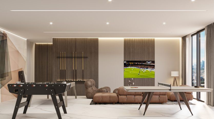 Un salon moderne dans un appartement de Dubaï comprenant une grande télévision diffusant un match de football, une élégante table de baby-foot, des canapés en cuir marron et un mur d'accent en bois avec des étagères élégantes.