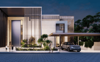 Maison moderne de deux étages à l'architecture minimaliste, présentant des lignes épurées et un mélange de lattes de bois et de façades en pierre lisse. On voit une famille se diriger vers l'entrée tandis qu'une voiture est garée sous un parking adjacent.