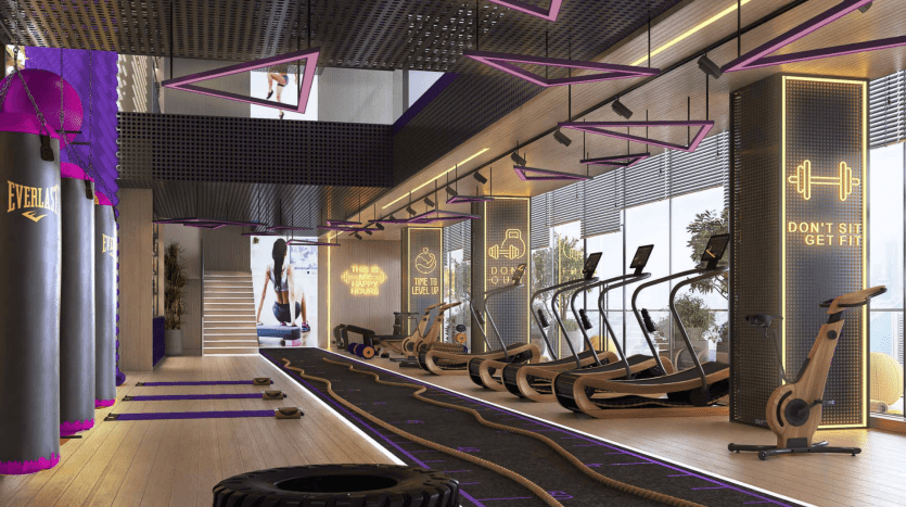 Un intérieur de salle de sport moderne comprenant des tapis roulants, des vélos d'exercice, des zones de musculation avec une ambiance globale dynamique et élégante éclairée par un éclairage suffisant dans un appartement haut de gamme à Dubaï.