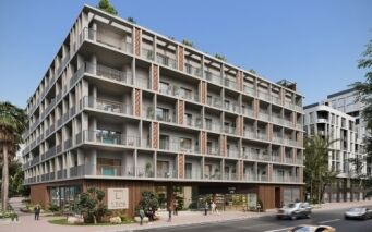 Un immeuble d'appartements moderne à Dubaï avec plusieurs balcons, de grandes fenêtres et des espaces commerciaux au rez-de-chaussée, entouré d'une verdure luxuriante et de rues fréquentées par des voitures et des piétons.