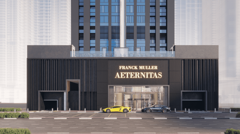 L'image montre une devanture Franck Muller Aeternitas élégante et moderne avec une façade noire, située entre de grands immeubles à Dubaï. Deux voitures sont garées devant le magasin sur un parking spacieux.