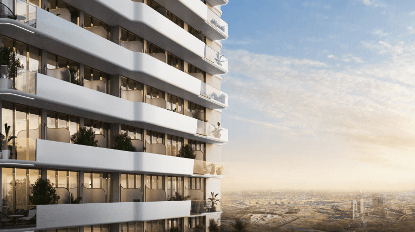 Bâtiment résidentiel moderne de plusieurs étages avec de grands balcons, de vastes façades vitrées et des plantes d'intérieur au coucher du soleil, surplombant un vaste paysage urbain de Dubaï.
