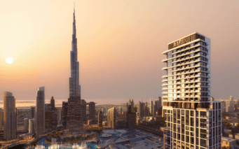 Vue du coucher de soleil sur l'horizon de Dubaï avec un grand gratte-ciel et des bâtiments modernes baignés de lumière dorée.