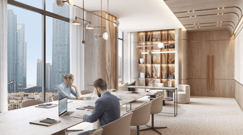 Deux personnes travaillent sur des ordinateurs portables dans un bureau moderne et luxueux doté d'un mobilier élégant et d'une vue sur la ville de Dubaï. L'espace présente un éclairage élégant et une décoration élégante.