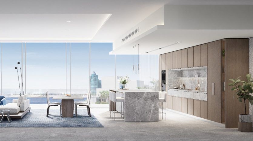 Salon moderne décloisonné avec un mobilier élégant donnant sur un paysage urbain à travers de grandes fenêtres, comprenant un coin salon, un îlot de cuisine et des touches de bois dans un appartement de Dubaï.
