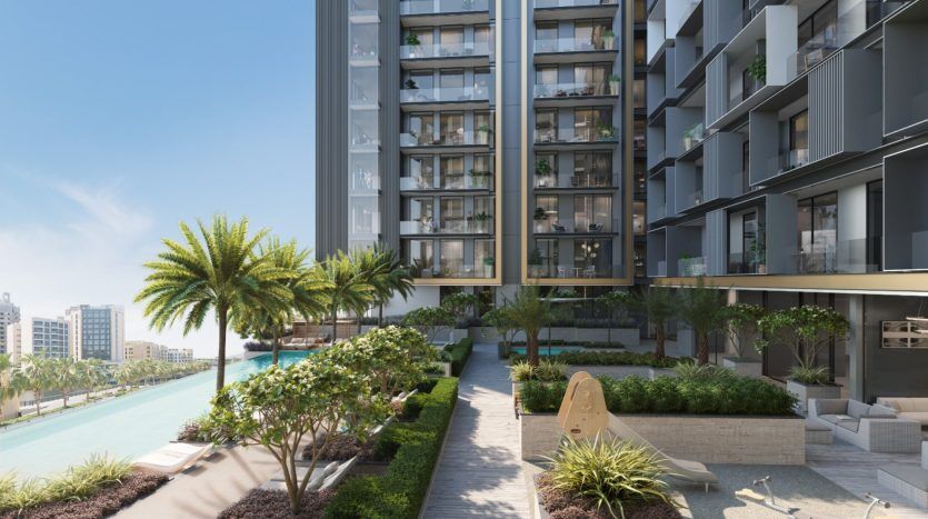 Villa résidentielle moderne de grande hauteur à Dubaï avec un aménagement paysager luxuriant comprenant des palmiers et des arbustes. Une passerelle pavée et un coin salon au bord d'un canal sont visibles sous un ciel bleu clair.