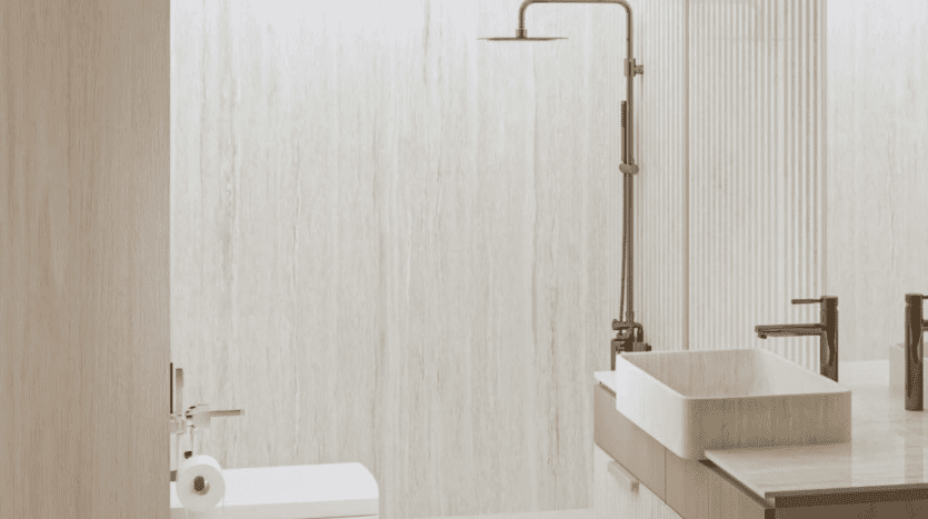 Une salle de bains moderne dans une villa de Dubaï comprenant un lavabo rectangulaire sur un comptoir en bois, un grand robinet et une serviette montée sur le côté. La pièce est réalisée dans des tons neutres avec des murs texturés.