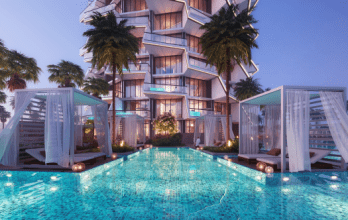 Luxurious hotel pool at dusk with illuminated cabanas and a modern, geometric Dubai villa in the background, reflecting off the sparkling turquoise water.