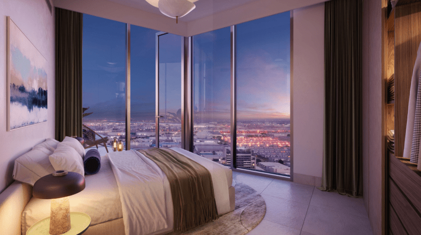 Une chambre luxueuse dans un appartement de Dubaï avec un grand lit, un mobilier moderne et de hauts murs de verre offrant une vue panoramique sur les lumières rougeoyantes de la ville au coucher du soleil.