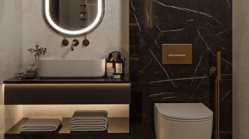 Une salle de bains luxueuse dans un appartement de Dubaï avec un mur en marbre foncé, un miroir ovale rétroéclairé et une vanité flottante. Des luminaires en laiton complètent la scène, avec des serviettes soigneusement pliées et un décor minimaliste améliorant l'ambiance.