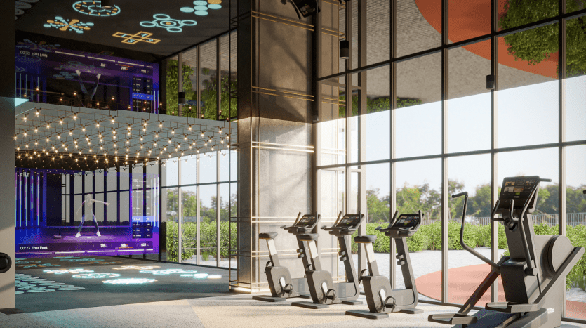 Modern gym with treadmills facing large windows overlooking a sunny park, adjacent to a lively space with neon lights and digital screens in a high-end apartment in Dubai.