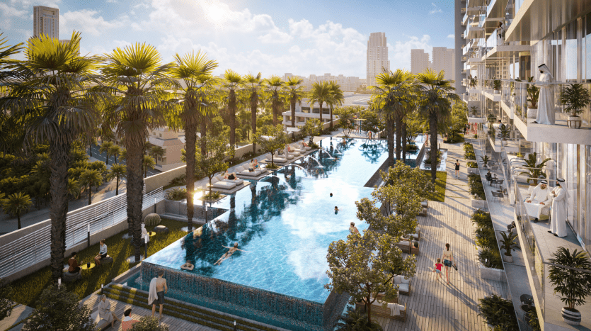 Luxurious rooftop pool surrounded by palm trees with people swimming and sunbathing, adjacent to a modern high-rise building in Dubai.