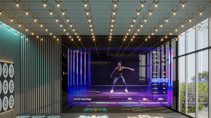A woman leads an interactive fitness class, displayed on a large digital screen in a modern LED-lit room with digital stickers and illuminated floor panels in a luxurious Dubai villa.
