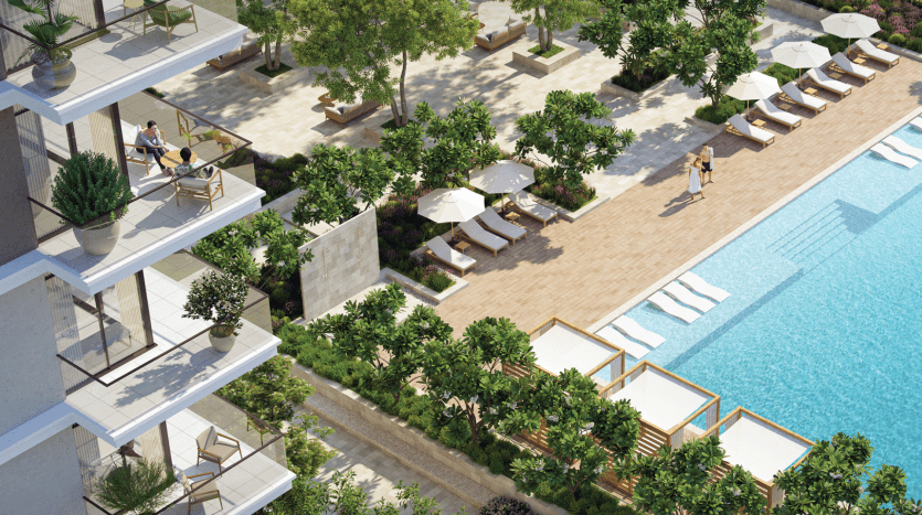 Une piscine extérieure luxueuse entourée de plantes et d'arbres luxuriants, dotée de chaises longues, de tables ombragées et d'une terrasse pour se promener. On voit des gens se détendre et se promener dans l’environnement serein d’une villa de premier ordre à Dubaï.