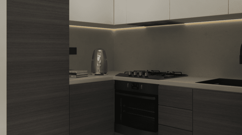 Une cuisine moderne dans une villa de Dubaï avec des armoires gris foncé, des appareils électroménagers intégrés et un éclairage sous les armoires mettant en valeur un dosseret beige clair.
