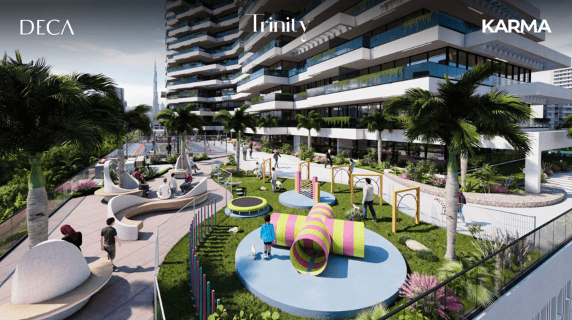 Un complexe d'appartements moderne à Dubaï avec des bâtiments de marque nommés DECA, Trinity et KARMA, comprenant un espace extérieur paysager avec des structures de jeux et des sièges entourés d'une verdure luxuriante.