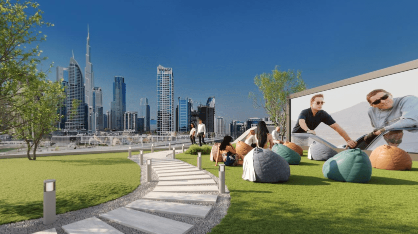 Les gens profitent d’une activité de plein air dans un parc urbain moderne de Dubaï, avec deux hommes jouant à un jeu et d’autres se relaxant sur des poufs, sur fond de gratte-ciel sous un ciel dégagé.