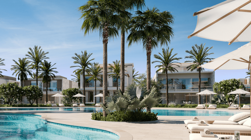 Une piscine luxueuse entourée de palmiers, de cabanes et de chaises longues sous un ciel bleu clair. L'architecture moderne des villas blanches complète l'aménagement paysager tropical.