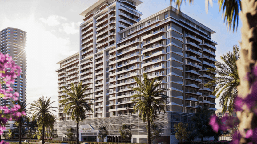 Immeubles modernes de grande hauteur à Dubaï sous un ciel clair, entourés de palmiers et de fleurs roses éclatantes au premier plan.