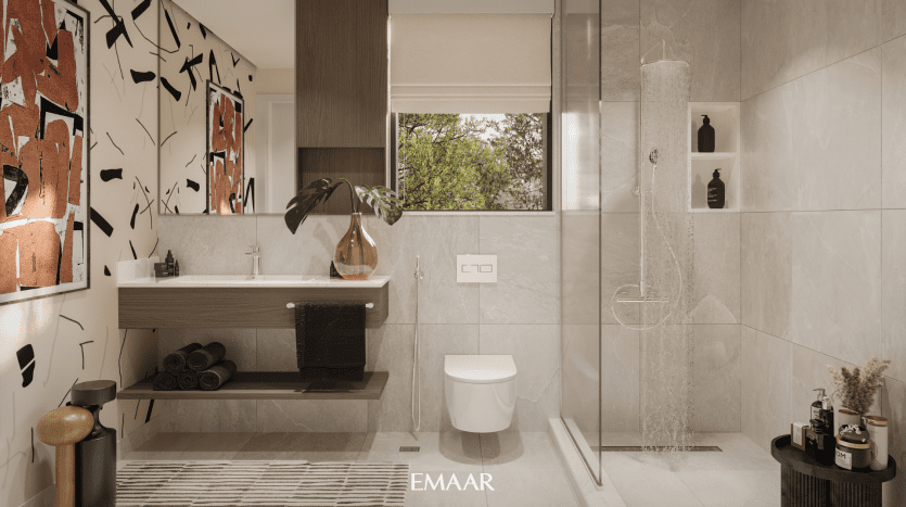 Salle de bains moderne avec murs en carrelage beige, douche à l'italienne, meuble-lavabo mural avec lavabo et miroir agrémenté de motifs décoratifs et de plantes dans une villa de Dubaï.