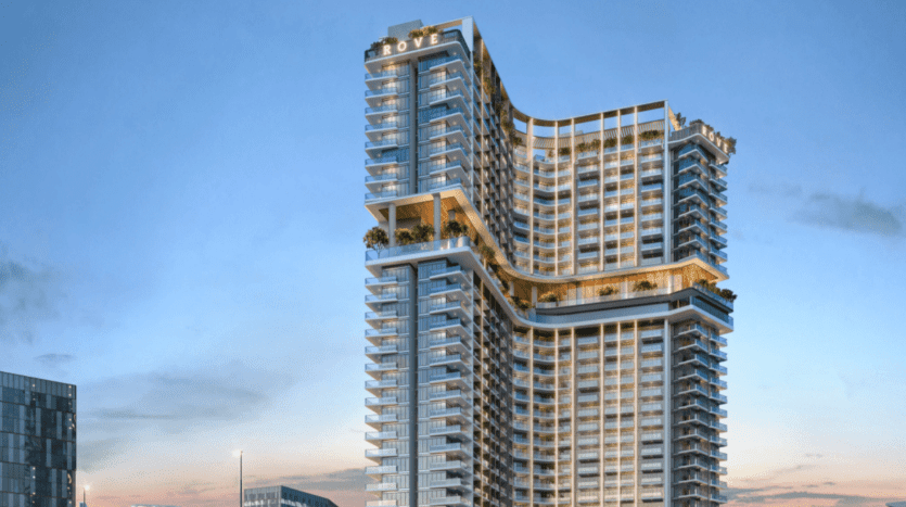 Deux immeubles modernes de grande hauteur au crépuscule, dotés de plusieurs balcons et de grandes terrasses avec des plantes vertes luxuriantes, sur un ciel dégagé. Les bâtiments affichent un style architectural contemporain avec le nom « ROVE » au sommet, représentant l'immobilier premium Dubaï.