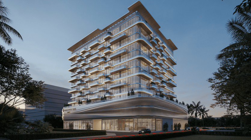 Un immeuble de grande hauteur moderne éclairé au crépuscule, doté de plusieurs balcons, de vastes façades vitrées et d'une base incurvée, entouré d'une verdure luxuriante et de palmiers. Une vitrine idéale pour une agence immobilière Dubaï spécialisée dans les propriétés de luxe.