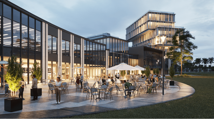 Immeubles de bureaux modernes à Dubaï au crépuscule avec des gens socialisant dans un coin salon extérieur animé entouré de palmiers et de sentiers éclairés.