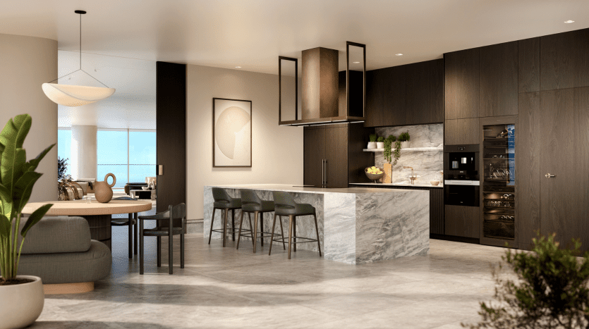 Une cuisine moderne dans un appartement de Dubaï avec des armoires en bois sombre, un îlot en marbre avec des tabourets verts, des appareils électroménagers en acier inoxydable et un coin repas en arrière-plan. La lumière naturelle illumine la pièce.