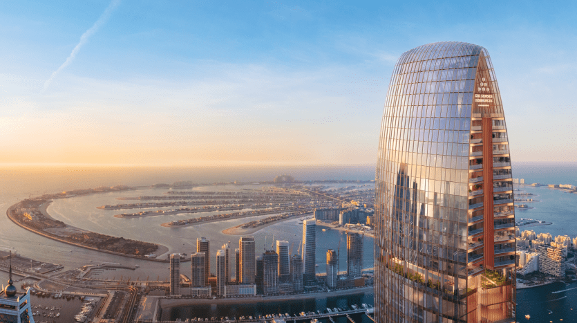 Vue aérienne d'une ville moderne au lever du soleil, avec un gratte-ciel incurvé au premier plan surplombant une zone côtière avec une série d'îles artificielles près de Dubaï.